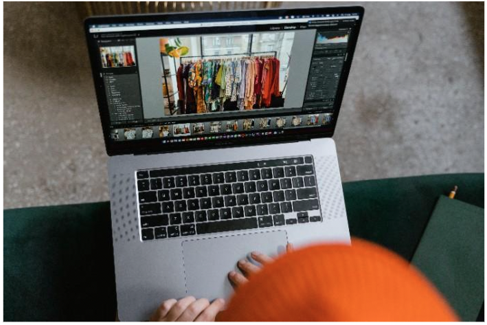 person editing a photo of clothing on a rack on a laptop